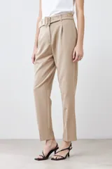Pantalón de vestir color beige, de corte recto, con pinzas, bolsillos laterales y cinturón con hebilla forrada.