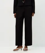 Pantalón de sastrería color negro con corte recto y estructura firme. Presenta cintura con pasadores, cierre frontal y bolsillos traseros embutidos. Incluye un cinturón fino con hebilla metálica.