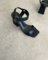 Sandalia de taco cuadrado alto, con diseño de punta cuadrada, tira delantera ancha y tira ajustable en el tobillo con hebilla metálica.