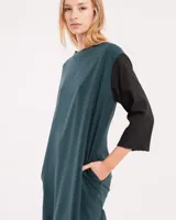 Vestido corto negro con mangas 3/4 verdes, cuello bote y bolsillos laterales.