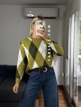 Sweater de tejido de punto con diseño de rombos en tonos verde oliva, verde oscuro y blanco. Presenta cuello redondo, mangas largas con puños acanalados y un corte holgado.