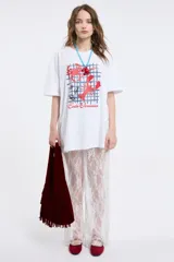 Remera de corte oversized en color blanco, con cuello redondo y mangas cortas. Presenta una estampa central con la frase 'Living a hot life' y un diseño de ajíes rojos.