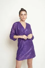 Vestido corto de lentejuelas color violeta, con escote en V cruzado, mangas tres cuartos abullonadas y ajuste en la cintura.