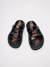 Sandalias de cuero vacuno color marrón con acabado brillante, diseño de dos tiras anchas acolchadas y plataforma baja.