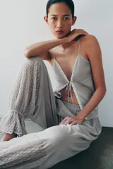 Pantalón abombacho semitransparente de tejido de encaje suave color gris, con tiro medio, cintura elástica y diseño con calados y volantes en los tobillos.