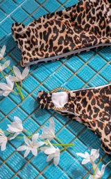 Traje de baño enterizo blanco con un solo hombro y aro dorado en la cadera.