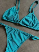 Conjunto de bikini color verde agua, con corpiño triangular de tirantes finos y bombacha cavada con tiras laterales.