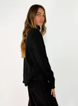 Sweater de punto color azul marino, con cuello alto, manga larga y puños acanalados. Presenta una costura vertical decorativa en el centro del frente y un ruedo acanalado con terminación asimétrica.