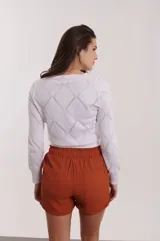 Sweater blanco de tejido de punto calado con diseño de rombos y flores bordadas en color naranja y verde.