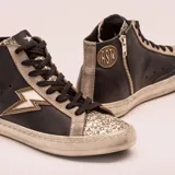 Zapatillas de media caña de cuero vacuno negro con puntera de glitter plateado, cordones negros y suela de goma. Presentan un rayo plateado en el lateral.