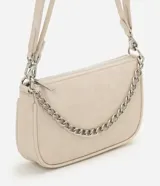 Cartera de mano tipo baguette, de color beige, con cierre superior de cremallera y una cadena decorativa plateada en la parte frontal. Cuenta con una correa larga ajustable y extraíble para usar al hombro o cruzada.