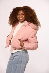 Campera bomber de nylon color rosado, con diseño acolchado, cierre frontal con cremallera y botones a presión, y capucha con borde de piel sintética al tono.