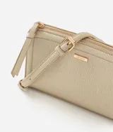 Cartera bandolera Satinato de material sintético en color dorado, con formato rectangular compacto y doble compartimiento con cierre. Cuenta con bolsillo frontal independiente, tiradores alargados y asa larga regulable y removible.