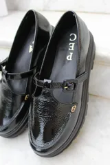 Zapato tipo guillermina de charol con suela track, cierre con tira y hebilla ajustable en el empeine.