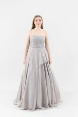 Vestido largo de tul color visón, con bordados de flores y metal. Corsé de encaje con terminación de blonda y falda con volados irregulares.