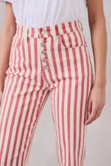 Pantalón de jean de corte recto, tiro medio, con estampado a rayas verticales rojas y crudas y cierre frontal con botones.