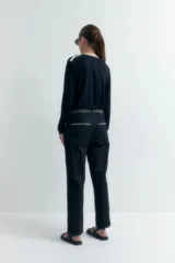 Pantalón negro de corte recto con bolsillos laterales y bordado en contraste blanco en cintura y bolsillos.