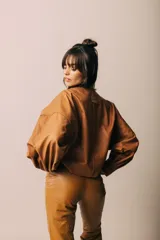 Campera de cuero con silueta oversize y corte levemente corto. Presenta cierre frontal metálico, cuello a la base y mangas amplias con detalles trenzados y recortes que aportan textura.