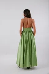Vestido midi de color verde, con escote en V profundo, banda ancha bajo el busto y falda amplia con gran volumen. Presenta espalda baja y cierre invisible.