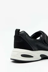 Guillermina deportiva Paddock Willemina, de color negro con suela blanca, capellada combinada de malla y material sintético, y tira con cierre de velcro en el empeine.