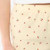 Pantalon corto de pijama amarillo con estampado all-over de cerezas y terminaciones con volados en el ruedo.