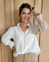 Blusa de algodón con diseño bicolor, presentando cuerpo en color blanco y mangas largas en tono beige. Posee cuello mao con volados, mangas abullonadas con puños elásticos y un corte holgado.