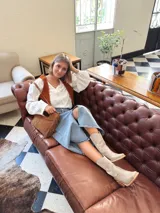 Cartera bandolera de cuero color camel, con forro interno de tela y flecos laterales.