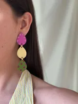 Aros colgantes con tres figuras geométricas: gota fucsia con detalles dorados, círculo dorado y gota verde con lunares fucsias.
