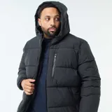 Campera acolchada tipo puffer color negro, con capucha fija, cierre frontal completo y bolsillos laterales y en el pecho con cierre.