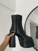 Botas negras de caña media con plataforma doble y taco cuadrado alto. Cierre lateral con cremallera.