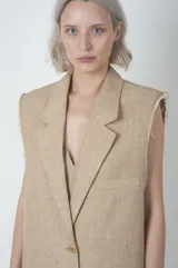 Chaleco largo color beige de lino y viscosa, con solapas y cierre con dos botones.