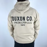 Canguro color tostado con capucha, corte oversize y estampado en la espalda con la leyenda "DUXON CO.", texto en japonés y "TOKYO".