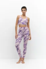 Calza deportiva de tiro alto con estampado tie-dye en tonos violeta y lila, confeccionada en tejido elástico y transpirable.