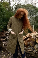 Campera reversible de corte largo, con diseño acolchado de rombos en color verde militar de un lado y estampado de rayas del otro. Presenta cuello redondo, cierre frontal con botones a presión y bolsillos laterales.