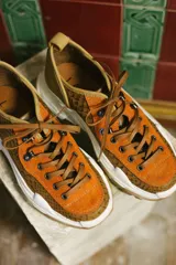 Zapatillas urbanas color óxido, con cordones marrones, suela gruesa blanca y detalles en cuero texturizado.