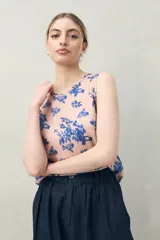 Top sin mangas de silueta recta y caída liviana, color rosado con estampado floral abstracto en azul. Presenta escote redondo.