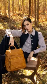 Mochila de símil cuero color marrón, con apertura superior, dos bolsillos frontales con cierre metálico y bolsillos laterales. Incluye tres bolsillos internos y correa extraíble.