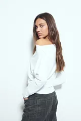 Top de manga larga con escote bote amplio, diseñado para usar ligeramente caído sobre los hombros. Presenta una silueta entallada y tejido liso, liviano y adaptable al cuerpo.