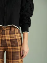 Cardigan negro de algodón con cierre frontal doble, cuello a la base y mangas tipo jamón con bordados en ochos y apliques de pompones. Presenta terminaciones acanaladas en contraste en cuello, puños y ruedo.