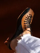 Zapato de cuero negro y marrón con cordones, detalle de textura símil cocodrilo y taco de madera.