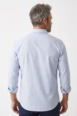 Camisa de manga larga con diseño de rayas verticales celestes y blancas, cuello camisero clásico y cierre frontal de botones.
