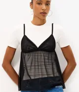 Remera baby tee de algodón con superposición de musculosa transparente de tul negro con breteles finos y escote en V.