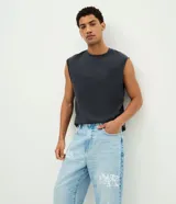Pantalón baggy de jean celeste con diseño estampado de grafitis en estilo lettering blanco. Cuenta con cintura con trabillas, cierre frontal de botón y cremallera, y bolsillos clásicos.
