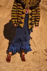 Pollera midi de tejido de punto con lúrex, color azul brillante. Presenta un diseño ajustado con elástico en la cintura, decorada con borlas distribuidas por toda la superficie y terminación con volados en el ruedo.