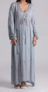 Vestido largo celeste con bordado de flores y espejos, escote en V con cordón ajustable, mangas largas abullonadas con puños elásticos y corte imperio.