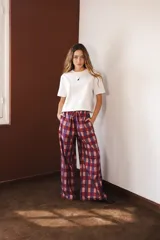Pantalón de corte holgado y tiro medio, con estampado de cuadros grandes en tonos bordó y violeta. Cuenta con cintura elástica con cordón ajustable y bolsillos laterales.