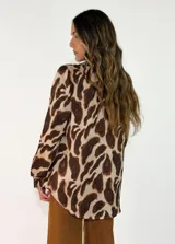 Camisa de manga larga con cuello camisero y cierre frontal de botones, confeccionada en tela fluida con estampado animal print en tonos marrones y negros.