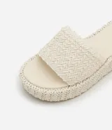 Sandalia tipo flatform con suela de plataforma plana y tira ancha superior, ambas con textura trenzada. Diseño sin cierre con puntera redonda.