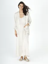 Conjunto color beige compuesto por vestido largo con breteles finos y saco con bolsillos delanteros.