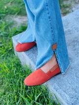 Mocasines color naranja de gamuza, con suela plana y detalle de etiqueta con logo en el lateral.